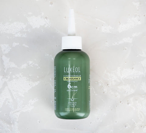 Product bottle macro on marble surface, Growth Conditioner texture and finish.