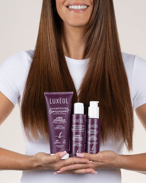 Женщина держит продукты ухода за волосами Luxéol на однотонном фоне